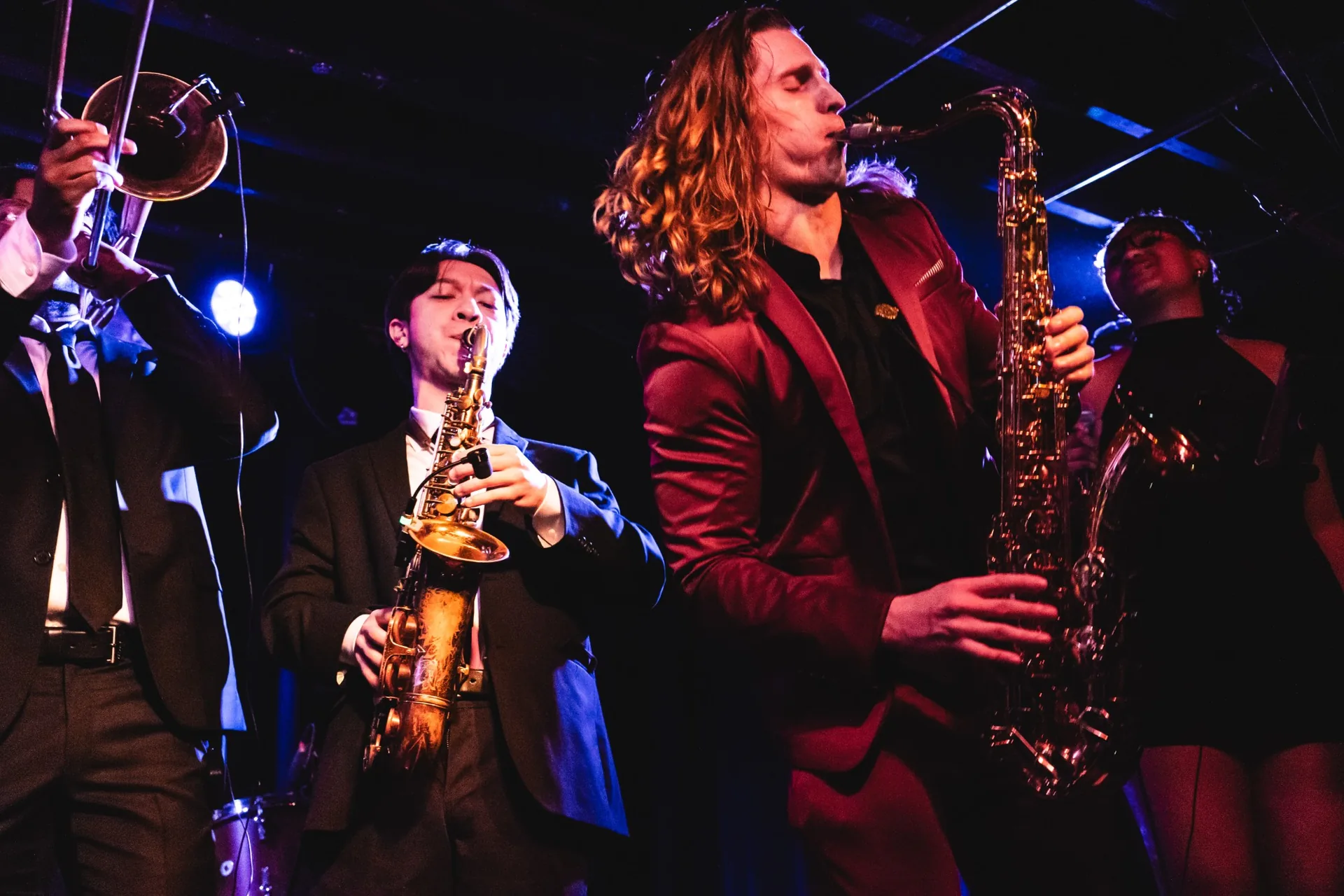 The full band performing live on a club stage under colored lights